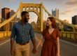 A diverse couple holding hands on a bridge with the Pittsburgh skyline in the background, symbolizing unity in interracial and intercultural relationships.