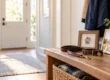 Leash and collar beside a framed paw-print keepsake in a sunlit entryway.