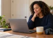 Adult at a home desk getting ready to prepare for online therapy, with a laptop, notebook, and headphones in a quiet room.