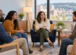 A small group of adults speaking with a facilitator in a calm counseling room