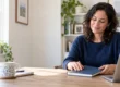 Adult closing a notebook beside a laptop after finishing a task